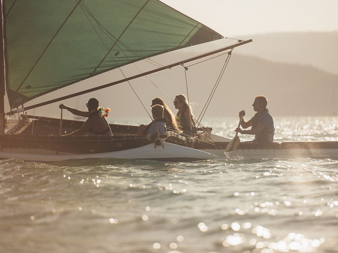 a group of people on a outrigger canoe in the water